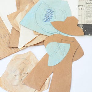 May include: A collection of brown and light blue paper sewing patterns featuring printed lines and shapes. The set includes various cut-out pieces and a rectangular instruction sheet with the visible text Sports briefs, WFL, and Douglas.