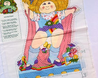 May include: A Cabbage Patch Kids doll fabric panel. The doll has blonde hair, blue bows, and a colourful outfit with rainbow and star details. Sewing instructions are printed on the panel, with measurements in centimetres.