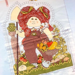 May include: A fabric panel featuring a Cabbage Patch Kid illustration. The character has red pigtails, brown overalls, and holds a shovel and a basket of produce. The panel includes instructions and the text "LEAVE OPEN FOR STUFFING".