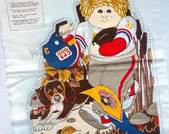 May include: A fabric panel with a Cabbage Patch Kids design. The illustration shows a boy in a football uniform with a football, a helmet, and a beagle. Instructions are printed on the left side of the panel.