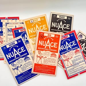 May include: A collection of vintage NuAce mounting corner packets in various colors including red, blue, yellow, black, and white. Each rectangular paper packet features the brand name, the color, a price of 10 cents, and illustrated instructions.