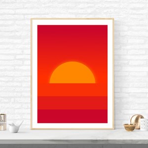 May include: A framed print of a minimalist sunset with a large orange sun setting over a red and orange horizon.