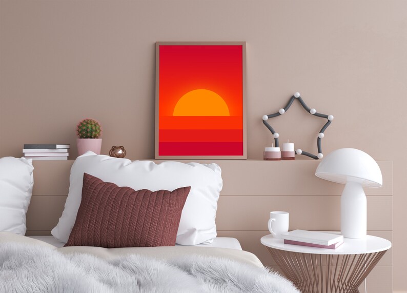May include: A framed print of a minimalist sunset with a red and orange color scheme. The print is hanging on a wall above a bed with white bedding and a brown throw blanket.