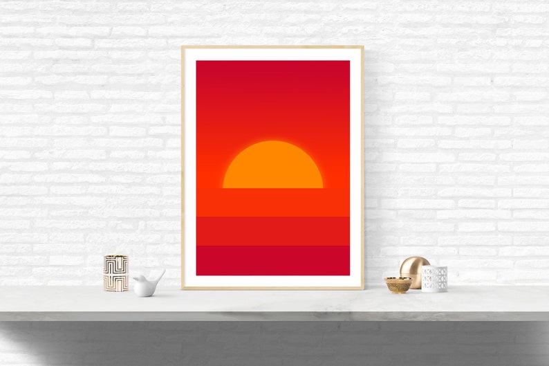 May include: A framed print of a minimalist sunset with a large orange sun setting over a red and orange horizon.