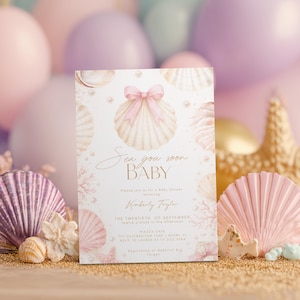 May include: A baby shower invitation with a seashell theme. The invitation features a watercolor seashell with a pink bow, surrounded by other seashells and pearls. Text on the invitation reads "Sea you soon BABY".