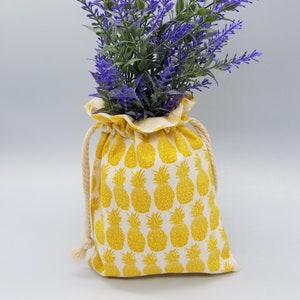 May include: A yellow drawstring bag with a pineapple pattern holds a bouquet of purple lavender flowers.
