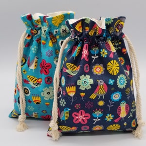 May include: Two drawstring bags with colorful bird and floral patterns. One bag is teal, the other is navy blue. Both have cream-colored drawstrings and white lining. The bags are suitable for small gifts or storage.