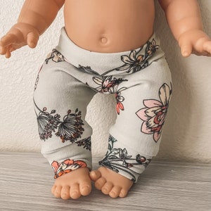 Può includere: Leggings grigie con motivo floreale rosa e arancione. Le leggings sono realizzate in un tessuto morbido ed elastico, perfette per l'uso quotidiano.