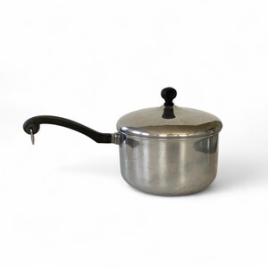 May include: A silver saucepan with a black handle and lid. The lid has a black knob on top.