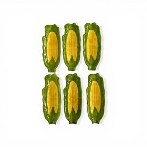 May include: Six ceramic corn-shaped serving dishes. Each dish features a yellow corn cob design with green husks. The dishes are arranged in two rows of three on a white background. The dishes are likely for serving food.