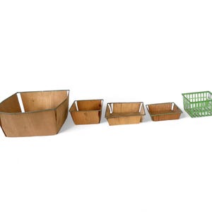 May include: Four wooden baskets of varying sizes, with a green wire basket in the background. The baskets are all rectangular and have a natural wood finish.