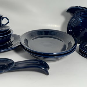 May include: A white ceramic mug with a black handle and the text "But First, Coffee" in a black, bold font. The mug is on a white surface. The mug is likely 11 ounces.