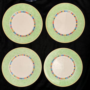 May include: Set of four green and white ceramic dinner plates with a colorful geometric design around the rim.