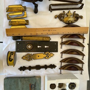 Puede incluir: Surtido de herrajes vintage que incluye pomos de puerta, tiradores de cajones, bisagras y una pequeña manivela de metal. La herrajería es de latón y tiene una variedad de estilos y acabados. También hay una regla, una lata de lubricante y un pequeño folleto de instrucciones.