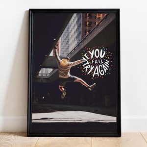 Può includere: Stampa incorniciata in nero raffigurante una persona che salta in un ambiente urbano. L'immagine include il testo "IF YOU FAIL TRY AGAIN" in un design colorato. La stampa è esposta su una parete bianca.