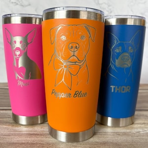 May include: Three stainless steel insulated tumblers in bright colors: pink, orange, and blue. Each tumbler features a silver engraved dog portrait and a name. The orange tumbler says "Pepper Blue". The pink tumbler says "Mia". The blue tumbler says "Thor".