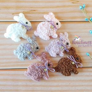 Peut inclure: Six petits ornements de lapin en peluche de différentes couleurs, dont blanc, rose, gris, marron et rose clair. Chaque lapin a un ruban violet et un charme de cloche dorée.