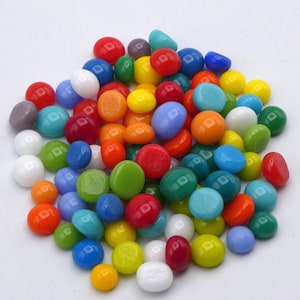 May include: A collection of colorful, smooth glass pebbles in various sizes and shades. The assortment includes red, orange, yellow, green, blue, and white pebbles. These decorative stones are ideal for crafts, home decor, or garden accents.