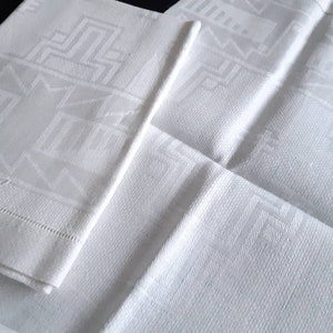 May include: Two white linen napkins with a geometric pattern. The napkins have a woven design and the text "FZ" is visible on one of the napkins.