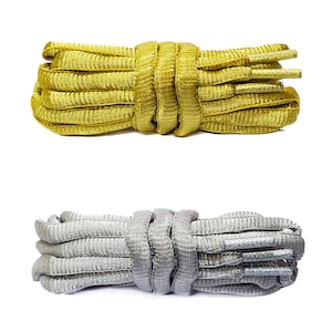 Peut inclure: Deux paires de lacets, une paire est dorée et l'autre est argentée. Les deux paires sont en matériau tissé.
