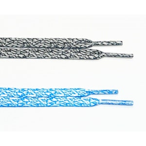 Puede incluir: Dos pares de cordones con fondo blanco y un patrón de rayo negro y blanco. Un par es negro y el otro es azul.