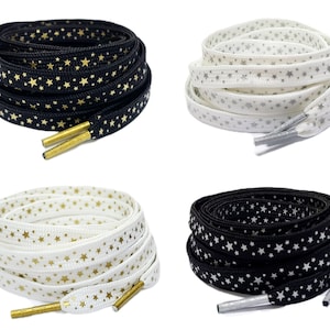 Pode incluir: Quatro pares de cadarços com um padrão de estrelas. Dois pares são pretos com estrelas douradas, e dois pares são brancos com estrelas prateadas.