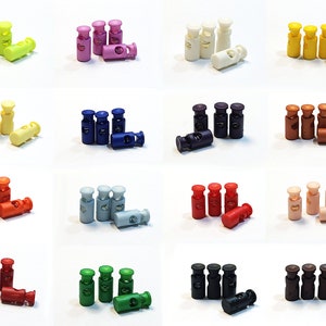 May include: Assortment of plastic cord locks in various colours, including yellow, pink, blue, purple, white, brown, red, grey, green, and black. Each cord lock has a spring-loaded mechanism for adjusting the length of a cord or rope.