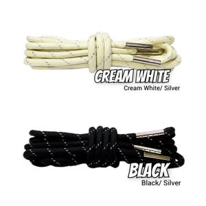 May include: Two sets of round shoelaces, one cream white and one black, both featuring reflective silver threading and metallic silver aglets. The text CREAM WHITE Cream White/ Silver and BLACK Black/ Silver is printed near the laces.