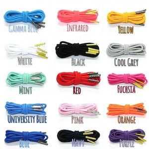 Op de afbeelding: Een selectie van veters in verschillende kleuren, waaronder gamma blauw, infrarood, geel, wit, zwart, koel grijs, mint, rood, fuchsia, universiteitsblauw, roze, oranje, blauw, marineblauw en paars. Elke veter heeft zilveren aglets en gouden tips.