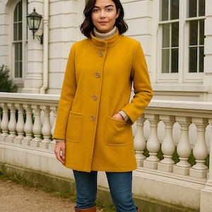 May include: A mustard-yellow coat with a high collar and three buttons. The coat has two front pockets and is worn with blue jeans and brown knee-high boots. The coat is approximately mid-thigh length.