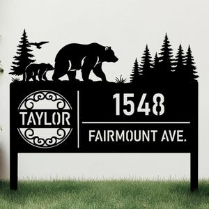 Può includere: Segno di indirizzo in metallo nero con una silhouette di famiglia di orsi, alberi e un uccello in volo. Il cartello mostra l'indirizzo "1548 FAIRMOUNT AVE." e il cognome "TAYLOR" in un cerchio decorativo.