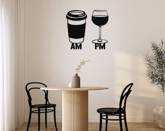 May include: Black metal wall art featuring a coffee cup and a wine glass, with "AM" and "PM" below. The art is mounted above a round wooden table and two black chairs, suggesting a dining or living area.