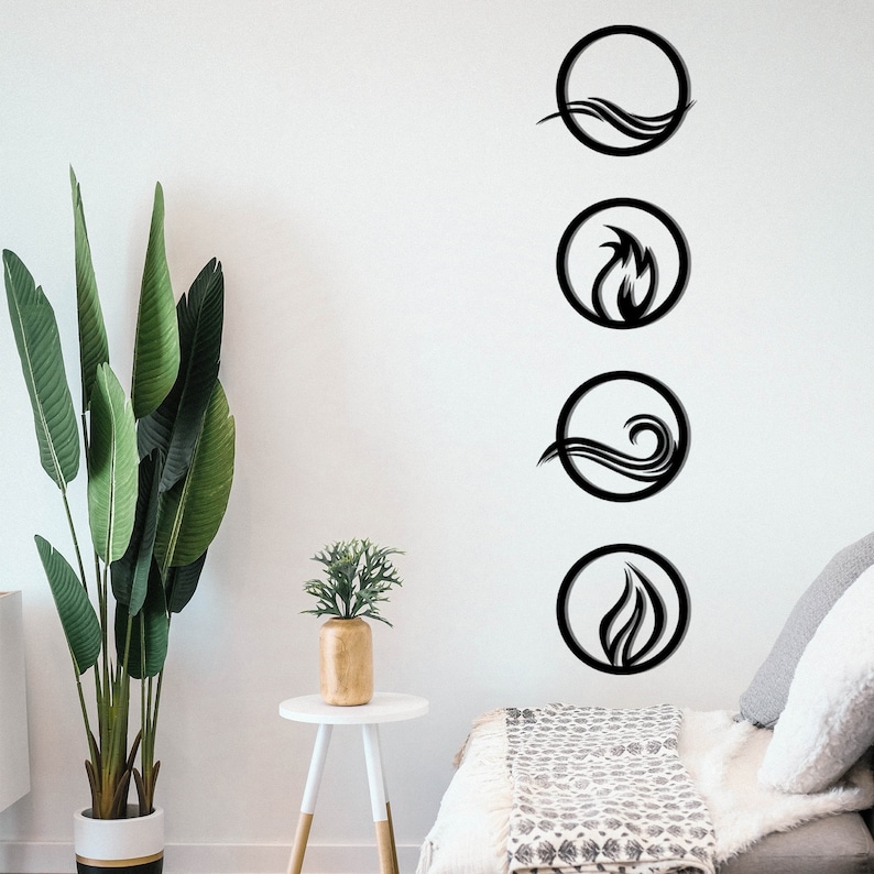 May include: Four black metal wall art pieces depicting the elements: water, fire, air, and earth. Each element is represented within a circular frame. The art is mounted on a white wall, with a large potted plant and a small side table in the foreground.