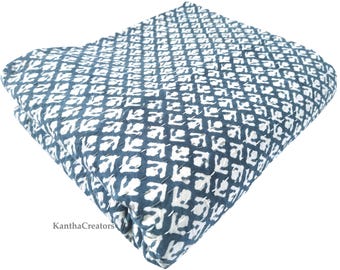 May include: A blue and white cotton quilt with a geometric pattern. The quilt is folded in half and the fabric is textured.
