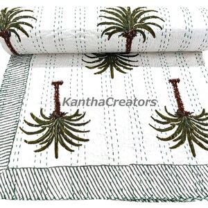Könnte beinhalten: Weiße Kantha-Steppdecke mit einem sich wiederholenden Palmenmuster in Braun und Grün. Die Steppdecke hat einen gestreiften Rand und ist mit grünem Faden handgenäht. Der Text "KanthaCreators" ist auf der Steppdecke sichtbar.