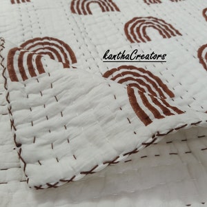 May include: A white cotton quilt with a brown stitched pattern of rainbows. The quilt is folded in half and the text "kanthaCreators" is visible in the center of the image.