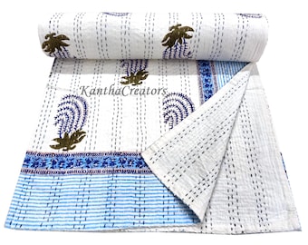 May include: White cotton kantha quilt with blue and white striped border and a floral pattern. The quilt is folded in half and the Kantha Creators logo is visible.