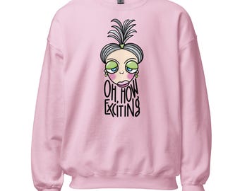 Può includere: Una felpa a maniche lunghe rosa chiaro con un'illustrazione a cartone animato di un personaggio con capelli grigi, palpebre verdi e guance rosa. Sotto il personaggio, il testo "OH, HOW EXCITING" in lettere nere stilizzate disegnate a mano.