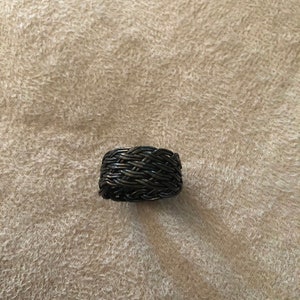 May include: A black woven ring made of metal wire.