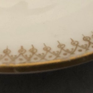 Puede incluir: Primer plano de un plato de cer&aacute;mica blanca con un borde dorado y un delicado patr&oacute;n dorado alrededor del borde.