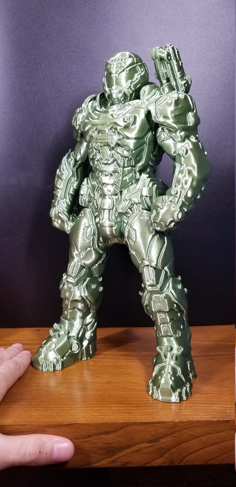 Pu&ograve; includere: Una action figure verde stampata in 3D di un personaggio di un videogioco. La figura &egrave; in piedi con le braccia lungo i fianchi e indossa un'armatura dettagliata.