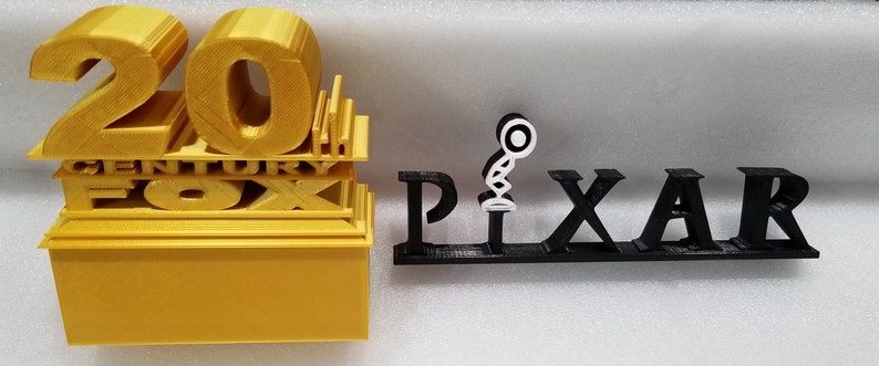 Pu&ograve; includere: Un modello stampato in 3D del logo della 20th Century Fox in oro, e un modello stampato in 3D del logo Pixar in nero con una lampada bianca.