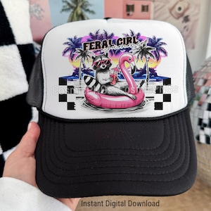 May include: Black and white trucker hat featuring a raccoon in sunglasses on a pink flamingo float. The hat has the words "FERAL GIRL SUMMER". The hat is held by a person. The hat has a black brim and a white front panel.