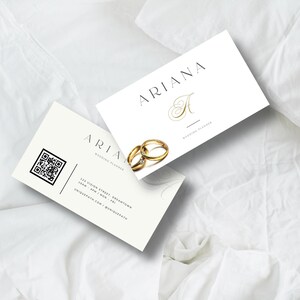 Op de afbeelding: Twee witte visitekaartjes met de tekst "ARIANA WEDDING PLANNER" en een gouden gestileerde letter "A". De kaart links heeft een QR-code en contactgegevens. De kaart rechts heeft twee gouden ringen.