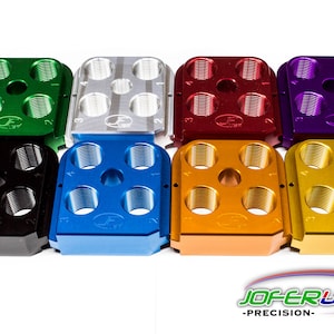 May include: A set of six reloading dies in various colors, including green, silver, red, purple, blue, and gold. Each die has six threaded holes and a central hole. The dies are made by JOFERUSA - PRECISION.