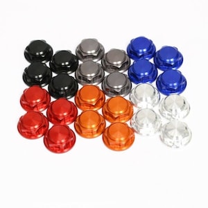 May include: An assortment of colorful, hexagonal-shaped metal nuts. The nuts are in various colors, including black, silver, red, orange, blue, and gray. The nuts are arranged in rows and columns on a white background.