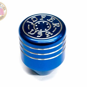 Puede incluir: Pomo de cambio de marchas de aluminio azul con detalles plateados y las palabras "JDFER USA" grabadas en la parte superior.