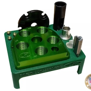 May include: Green reloading press with a black die and a green base. The press has a circular die holder with six holes for dies. The base has the text "FOR DIELON 650/750" printed on it. The press is made in the USA with pride.