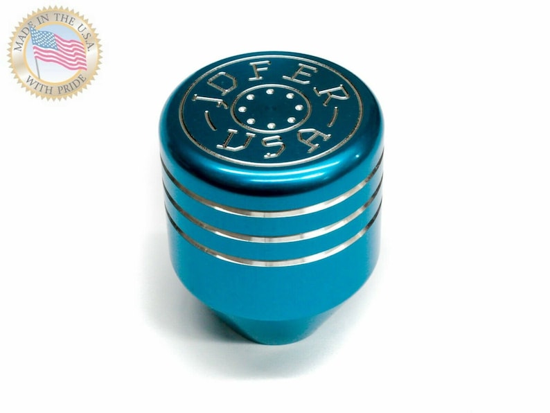 Puede incluir: Una palanca de cambios de color azul turquesa con una parte superior plateada y una inscripci&oacute;n plateada que dice "JOFER USA".