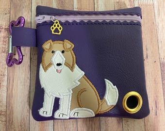 May include: Purple zippered pouch with a dog design. The dog is a brown and white Collie with a white chest and a brown tail. The pouch has a gold metal ring on the side.